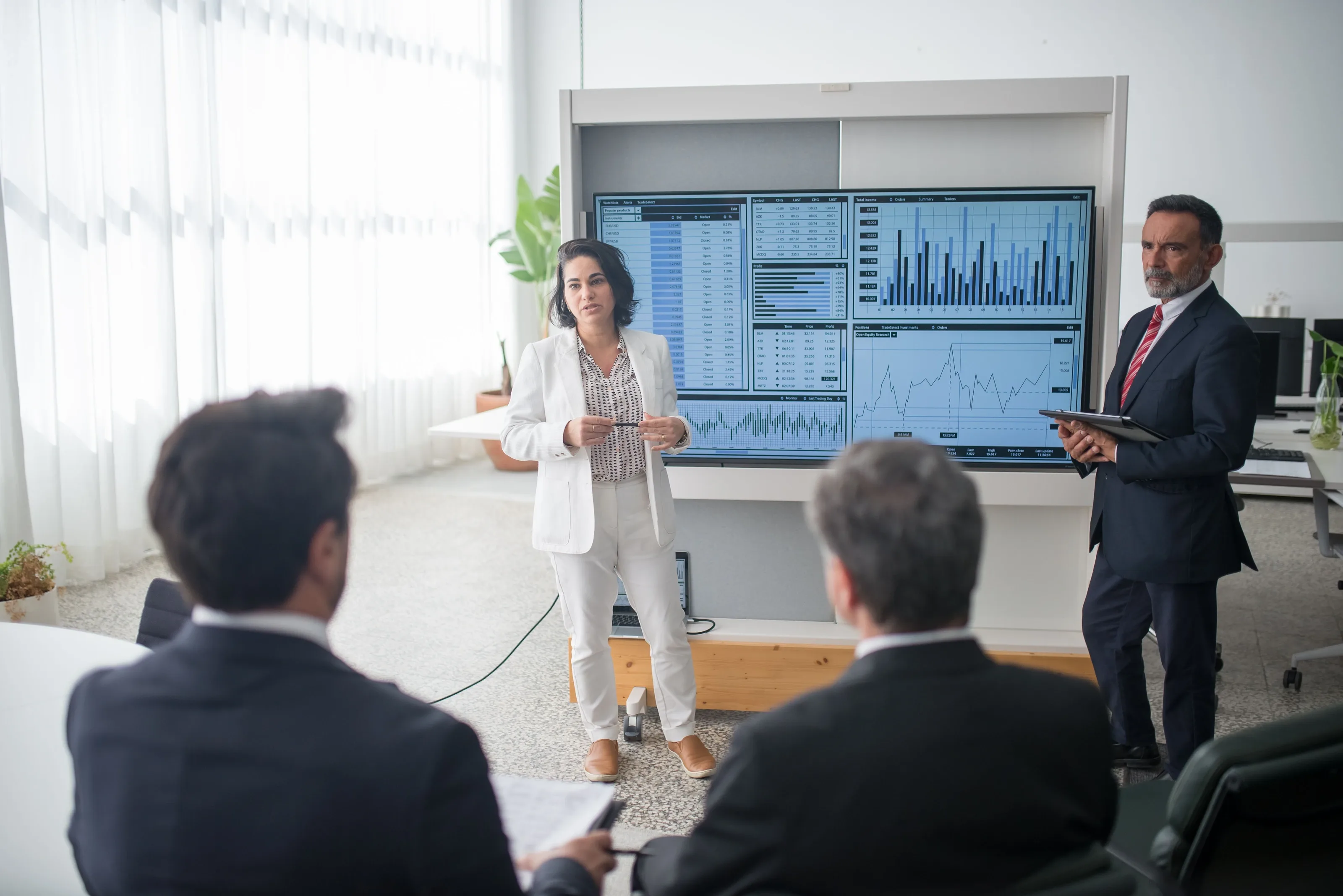 Presenter talking to a seated group in front of large screens
